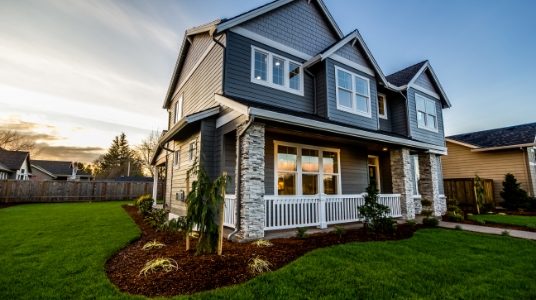 A modern home with blue siding, brick accents, and a white rail front porch.