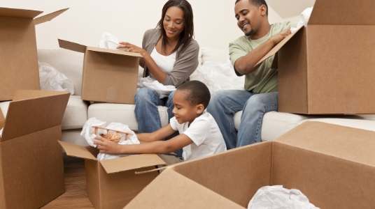 A family of three surrounded by moving boxes